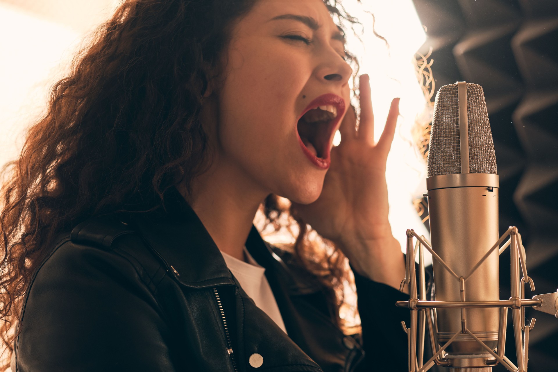 Pretty female singer recording in music studio